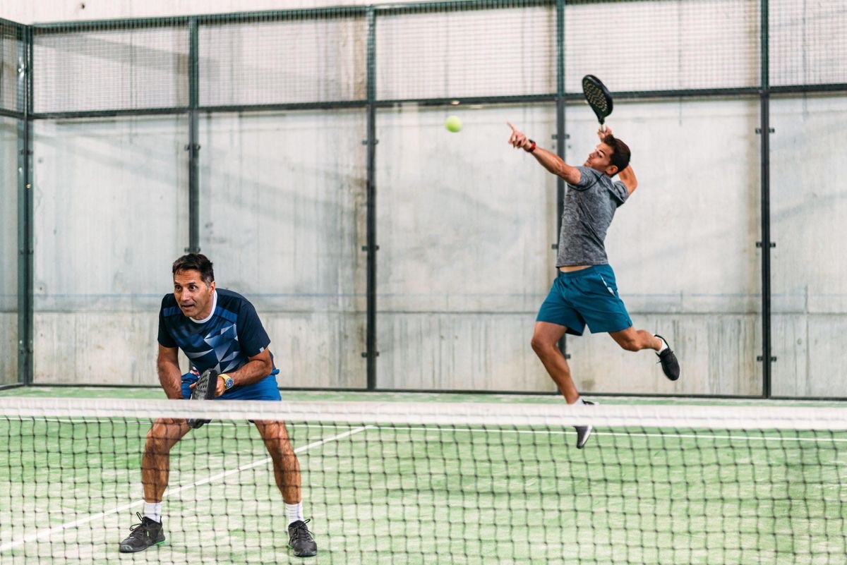 Deux joueurs de padel se tapent dans la main sur un terrain après un échange.