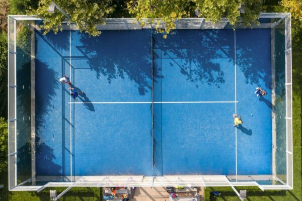 Actualités et conseils padel Vue aérienne d’un terrain de padel bleu avec des joueurs en pleine partie.